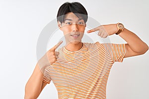 Young chinese man wearing casual striped t-shirt standing over isolated white background smiling cheerful showing and pointing