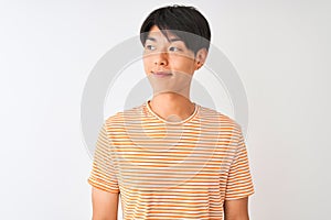 Young chinese man wearing casual striped t-shirt standing over isolated white background smiling looking to the side and staring