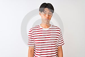 Young chinese man wearing glasses and striped t-shirt standing over isolated white background depressed and worry for distress,