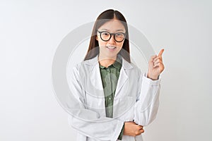 Young chinese scientist woman wearing coat and glasses over isolated white background with a big smile on face, pointing with hand