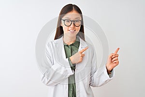 Young chinese scientist woman wearing coat and glasses over isolated white background smiling and looking at the camera pointing