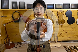 Young Chinese violin maker at work in her workshop