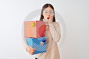 Young chinese woman holding birthday gifts over isolated white background afraid and shocked, surprise and amazed expression with