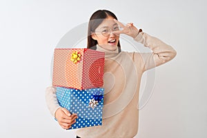 Young chinese woman holding birthday gifts over isolated white background Doing peace symbol with fingers over face, smiling