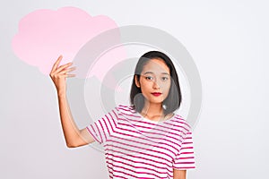 Young chinese woman holding cloud speech bubble standing over isolated white background with a confident expression on smart face