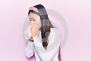 Young chinese woman illness wearing diadem using paper handkerchief on nose