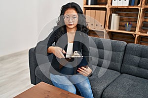 Young chinese woman psychologist holding clipboard speaking at clinic