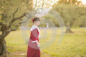 Young Chinese woman in red retro style dress, walking and traveling in a meadow field, France, Europe