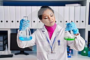 Young chinese woman scientist holding test tubes at laboratory