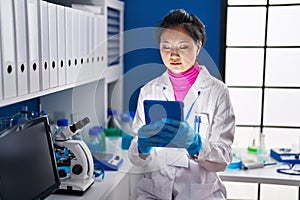 Young chinese woman scientist using touchpad at laboratory