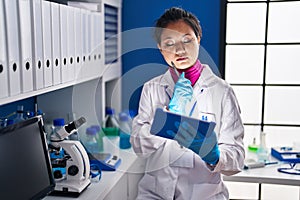 Young chinese woman scientist using touchpad at laboratory