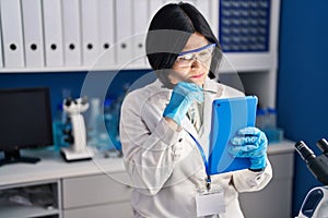 Young chinese woman scientist using touchpad working at laboratory