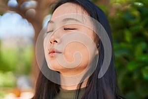 Young chinese woman scientist writing report reading book at park