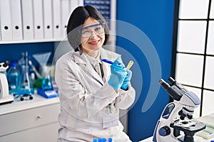 Young chinese woman scientist writing on test tube at laboratory