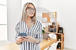 Young chinese woman smiling confident using smartphone at office