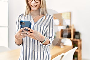 Young chinese woman smiling confident using smartphone at office