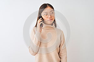 Young chinese woman talking on the smartphone over isolated white background smiling looking to the side and staring away thinking