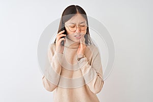Young chinese woman talking on the smartphone over isolated white background touching mouth with hand with painful expression
