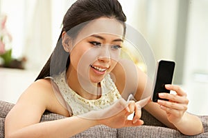 Young Chinese Woman Using Mobile Phone At Home