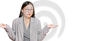 Young chinese woman wearing business clothes clueless and confused expression with arms and hands raised