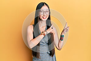 Young chinese woman wearing business dress and glasses smiling and looking at the camera pointing with two hands and fingers to