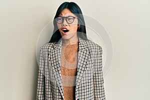 Young chinese woman wearing business style and glasses angry and mad screaming frustrated and furious, shouting with anger