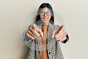 Young chinese woman wearing business style and glasses pointing to you and the camera with fingers, smiling positive and cheerful