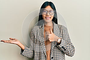 Young chinese woman wearing business style and glasses showing palm hand and doing ok gesture with thumbs up, smiling happy and