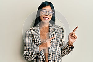 Young chinese woman wearing business style and glasses smiling and looking at the camera pointing with two hands and fingers to