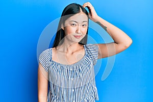 Young chinese woman wearing casual striped t-shirt confuse and wonder about question