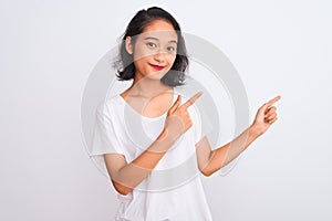 Young chinese woman wearing casual t-shirt standing over isolated white background smiling and looking at the camera pointing with