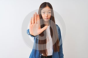 Young chinese woman wearing denim shirt standing over isolated white background doing stop sing with palm of the hand