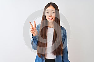 Young chinese woman wearing denim shirt standing over isolated white background showing and pointing up with fingers number two