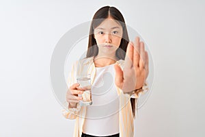 Young chinese woman wearing glasses drinking glass of water over isolated white background with open hand doing stop sign with