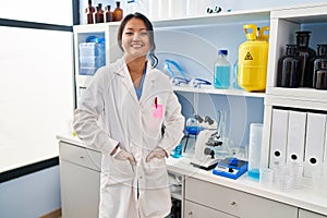 Young chinese woman wearing scientist uniform standing at laboratory