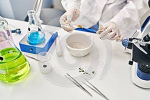 Young chinese woman wearing scientist uniform using syrup bottle at laboratory