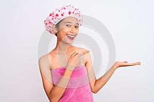 Young chinese woman wearing shower towel and cap bath over isolated white background amazed and smiling to the camera while