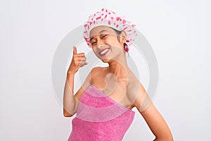 Young chinese woman wearing shower towel and cap bath over isolated white background smiling doing phone gesture with hand and