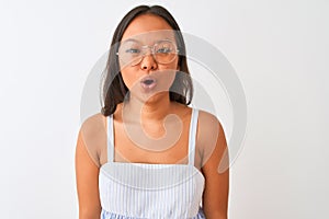 Young chinese woman wearing striped dress and glasses over isolated white background afraid and shocked with surprise expression,