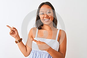 Young chinese woman wearing striped dress and glasses over isolated white background smiling and looking at the camera pointing