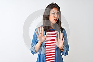 Young chinese woman wearing striped t-shirt and denim shirt over isolated white background Moving away hands palms showing refusal