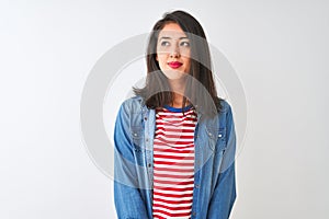 Young chinese woman wearing striped t-shirt and denim shirt over isolated white background smiling looking to the side and staring