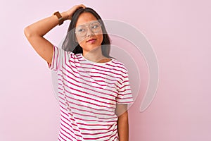 Young chinese woman wearing striped t-shirt and glasses over isolated pink background confuse and wonder about question