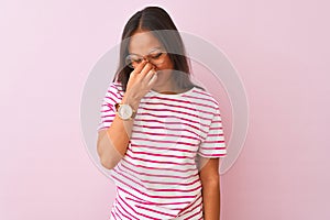 Young chinese woman wearing striped t-shirt and glasses over isolated pink background tired rubbing nose and eyes feeling fatigue