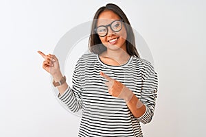 Young chinese woman wearing striped t-shirt and glasses over isolated white background smiling and looking at the camera pointing