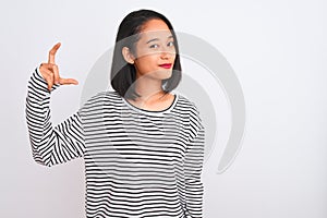 Young chinese woman wearing striped t-shirt standing over isolated white background smiling and confident gesturing with hand