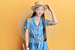 Young chinese woman wearing summer hat confuse and wonder about question