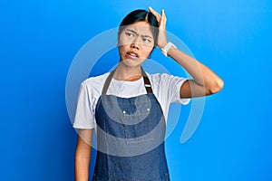 Young chinese woman wearing waiter apron confuse and wonder about question