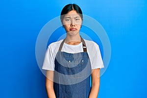 Young chinese woman wearing waiter apron depressed and worry for distress, crying angry and afraid