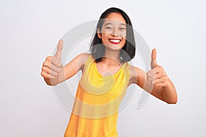 Young chinese woman wearing yellow casual t-shirt standing over isolated white background approving doing positive gesture with